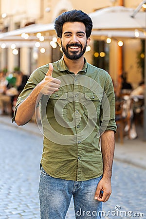 Happy man showing thumbs up, like sign positive something good positive feedback in city street Stock Photo