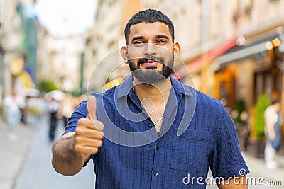 Happy man showing thumbs up, like sign positive something good positive feedback in city street Stock Photo