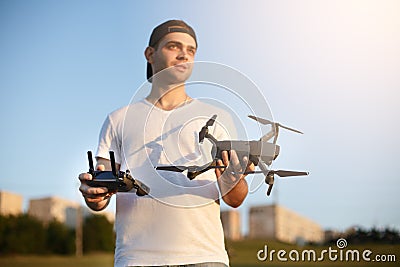 Happy man shows You small compact drone and remote controller. Pilot holds quadcopter and RC in his hands. Stock Photo