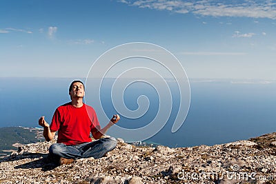 Happy man sits yoga pose on the mountain Stock Photo
