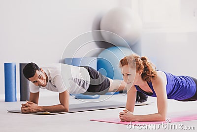 Happy man and sportswoman exercising on mat during physical training Stock Photo