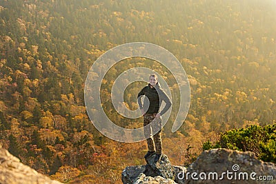 Happy man standing at the top of the mountain. Landscape view of misty autumn mountain hills and man silhouette Stock Photo