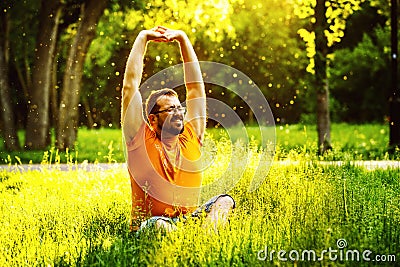 A happy man is stretching himself on green grass with squint eye Stock Photo