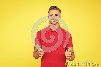 Happy man with stylish beard hair in red tshirt show thumbs ups satisfactory hand gesture yellow background Stock Photo