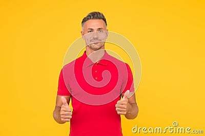 Happy man with stylish beard hair in red tshirt show thumbs ups satisfactory hand gesture yellow background Stock Photo