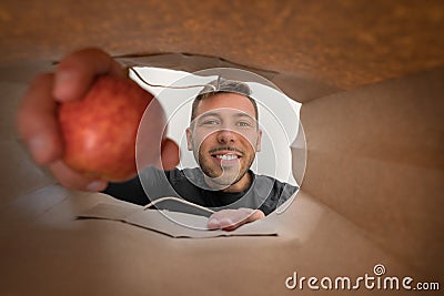 Happy man taking food out of paper bag. Home delivery from grocery shop during self quarantined, COVID-19. Stock Photo