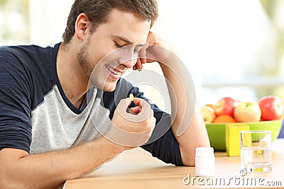 Happy man taking a vitamin pill at home Stock Photo