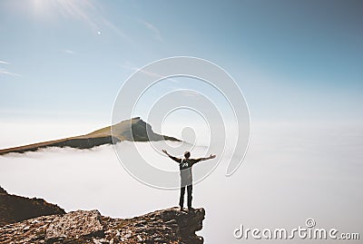 Happy man traveler standing alone on cliff edge mountain over clouds Stock Photo
