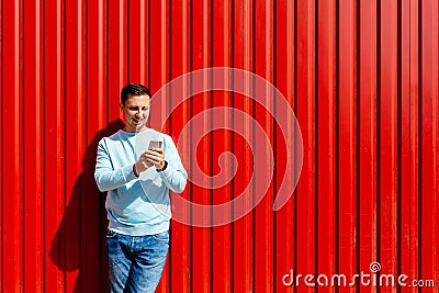 Man using smar phone on the background of red wall Stock Photo