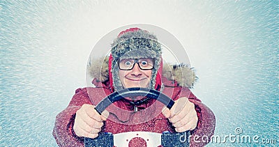 Happy Man in winter clothes with a steering wheel, snow blizzard. Concept car driver Stock Photo