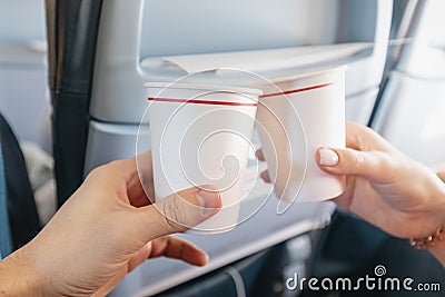 Man and a woman clink paper cups in the interior of an airplane during a vacation flight. Catering and wine tasting Stock Photo