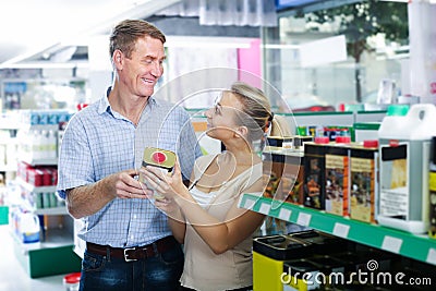 happy man and woman customers choosing can with protective furniture oil Stock Photo