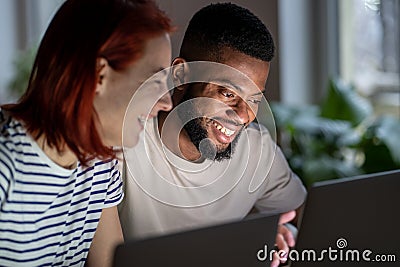 Happy man woman freelancers discussing project working on laptops looking at screen. Stock Photo