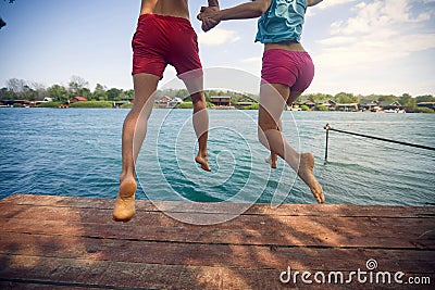 Man and woman jumping from a pier into the water Stock Photo