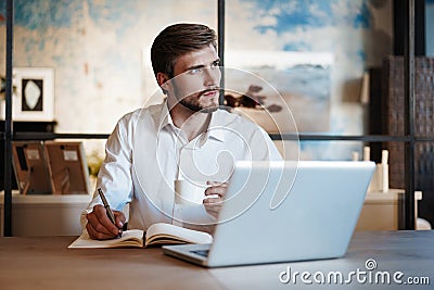 Happy man working at office, doing notes, sitting at desk. Stock Photo