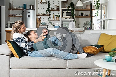 Happy married homosexual female gay couple laughing and embracing on the sofa with smile on their faces. Lesbian couple at home Stock Photo