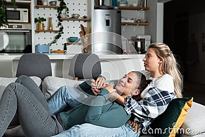 Happy married homosexual female gay couple laughing and embracing on the sofa with smile on their faces. Lesbian couple at home Stock Photo