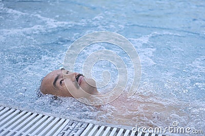 Happy mature asian man laying on water relax in outdoor thermal pool with hydromassage. Stock Photo