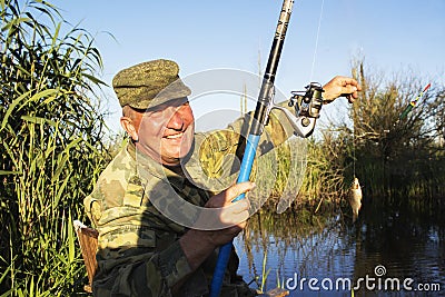 Happy mature fisherman with fresh caught crucian Stock Photo