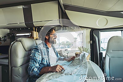 Happy mature man smilng inside a camper camping car using paper map guide to plan destinations holiday. Vanlife lifestyle Stock Photo