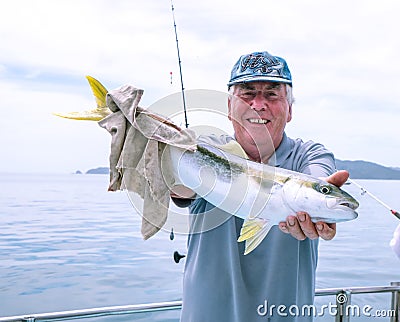 Happy mature senior caucasian tourist has caught a kingfish on a Stock Photo