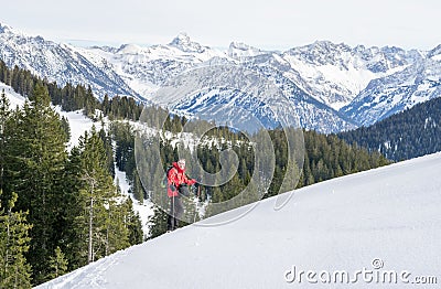 Senior man is snowshoe hiking in alpine snow winter mountains. Allgau, Bavaria, Germany. Stock Photo