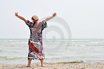 Happy mature woman enjoying breeze on seashore Stock Photo
