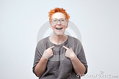 Happy mature woman with red hair pointing fingers at herself. Select me please concept Stock Photo