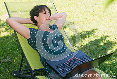 Happy mature woman relaxing resting on the deck chair in garden Stock Photo