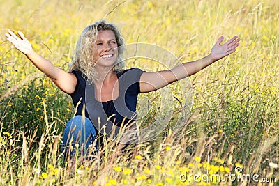 Happy mature woman spreading her arms in a meadow Stock Photo