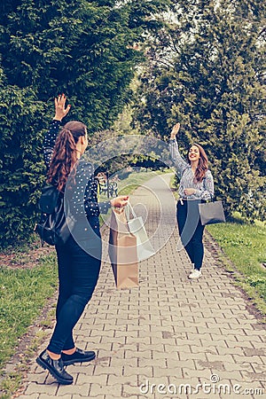Happy meeting of two female friends waving hands outdoors Stock Photo