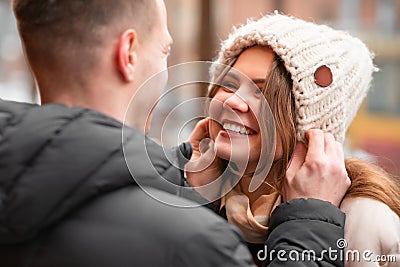 Happy man puts on a winter hat for his woman. The guy in love takes care of the girl Stock Photo