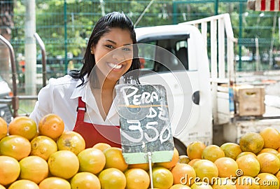 Happy mexican saleswoman with oranges on a farmers market Stock Photo