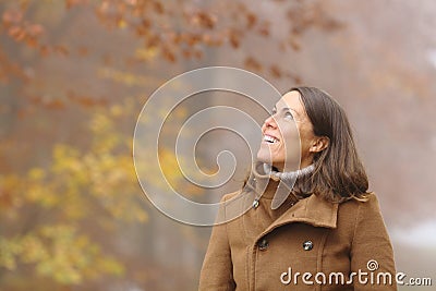 Happy middle age woman contemplating in a forest in fall Stock Photo