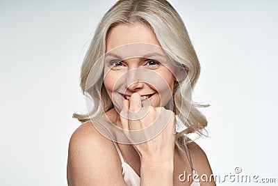 Happy middle aged blonde woman looking at camera advertising face skin care. Stock Photo