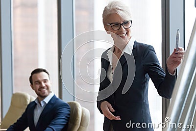 Happy middle-aged businesswoman coach mentor in suit drawing presentation Stock Photo