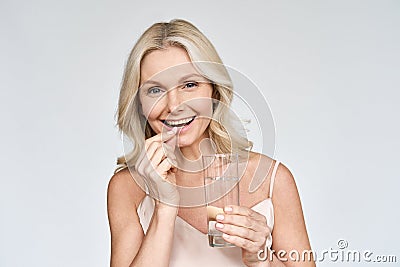 Portrait of happy smiling mid aged woman taking pills on white. Stock Photo