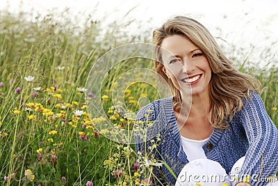 Happy middle aged woman in wild flower field Stock Photo