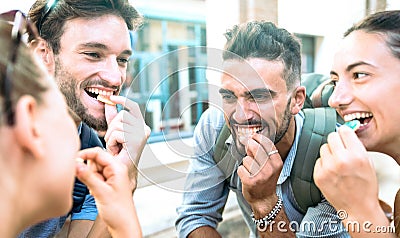 Happy millenial friends having fun at city center eating sugar candies - Z generation friendship concept with young millenial Stock Photo