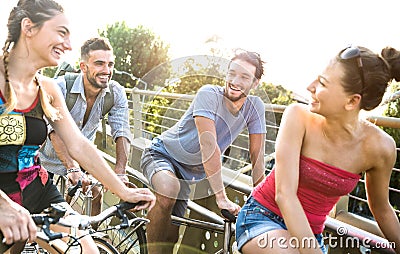 Happy millenial friends having fun riding bicycle in city park - Friendship concept with young millennial people students biking Stock Photo