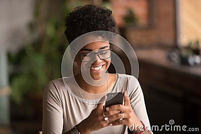 Happy millennial african american woman holding smartphone using ecommerce apps Stock Photo