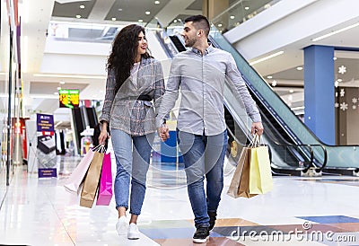 Happy millennial couple walking after shopping in mall Stock Photo