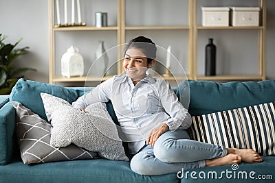 Happy millennial ethnic girl relaxing on sofa at home Stock Photo