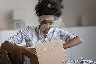 Happy millennial african american woman unpacking parcel. Stock Photo