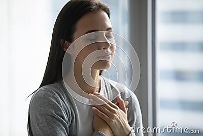 Happy millennial woman feel grateful or thankful at workplace Stock Photo