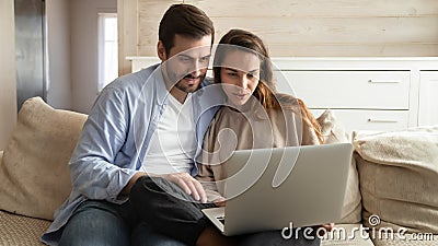 Happy millennial married couple looking at computer monitor at home. Stock Photo