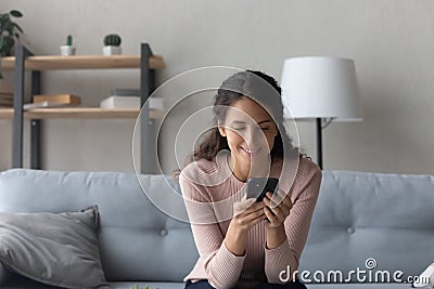 Happy millennial woman browsing internet on cellphone at home Stock Photo