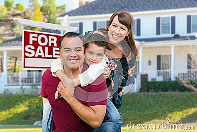 Happy Mixed Race Family In Front of House and For Sale Real Estate Sign Stock Photo