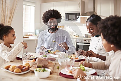 Happy mixed race young family of four eating Sunday dinner together, front view Stock Photo