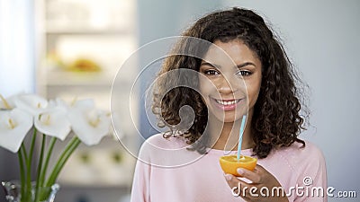 Happy mixed race young lady holding orange half, immune system protection, diet Stock Photo